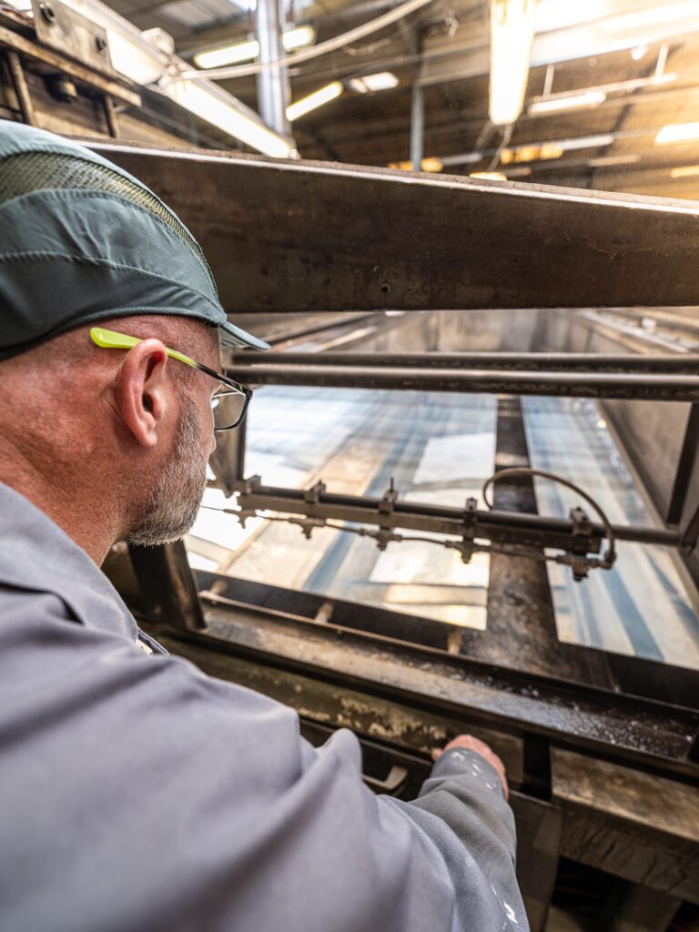 Op&eacute;rateur contr&ocirc;lant une plaque de verre sur une ligne de production AURYS